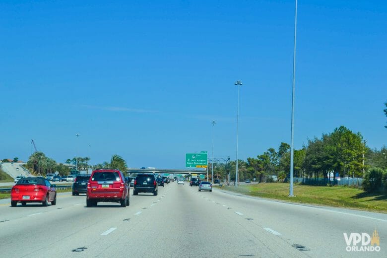 Imagem de uma rodovia em Orlando. Vários carros andam em 4 faixas, e há placas indicando o caminho à frente.