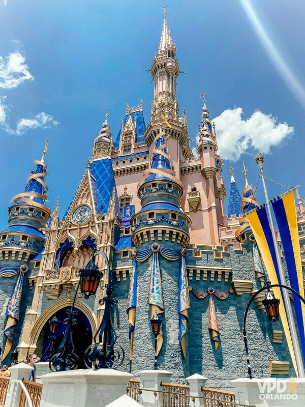 Castelo da Cinderela na Disney. Ele tem detalhes de laços azuis e dourados nas suas torres e nas laterais para o aniversário de 50 anos.