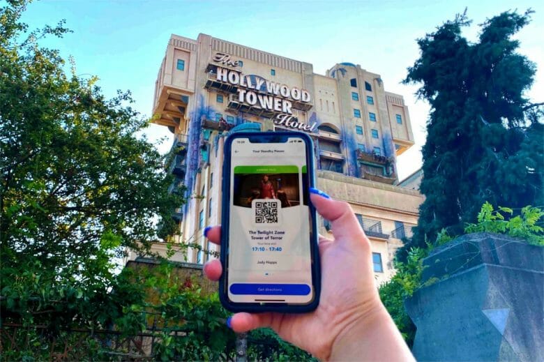 Uma mão segurando um celular
com o Standby Pass na tela e a Hollywood Tower ao fundo 