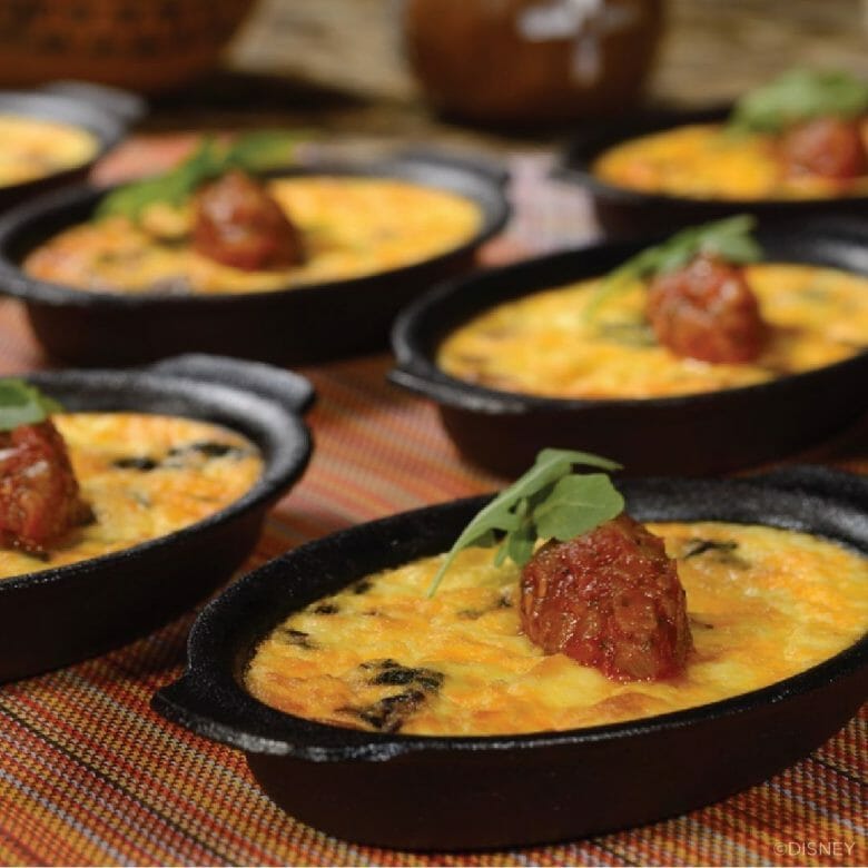 Imagem de vários pratos de comida do Boma, com o que parece ser um omelete com alguma carne em potinhos pretos de ferro.