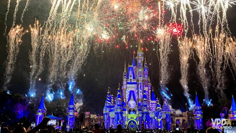 Foto do show de fogos, com o castelo iluminado com projeções e fogos estourando no céu.