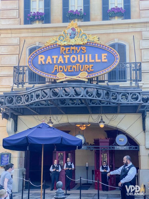 Foto da entrada da atração de Ratatouille, com a placa Remy's Ratatouille Adventure e Cast Members ao redor.