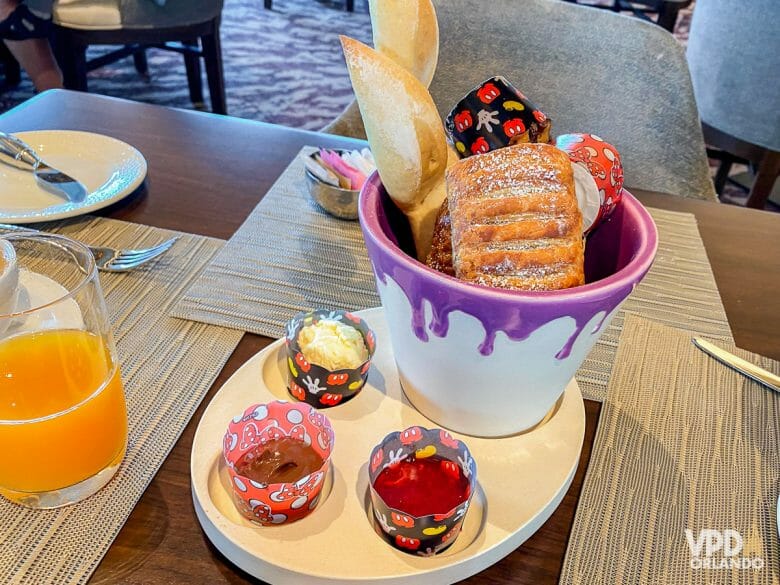 Imagem de uma cesta com vários pães e caldas no Topolino's Terrace, que oferece refeições com personagens.