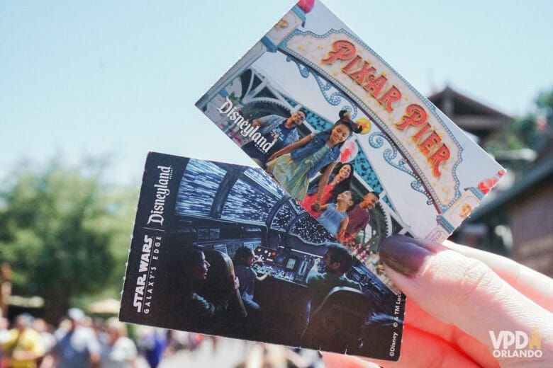 Foto de dois ingressos da Disneyland Califórnia sendo segurados, um com uma foto do Pixar Pier e outra com uma foto de dentro da Millennium Falcon.