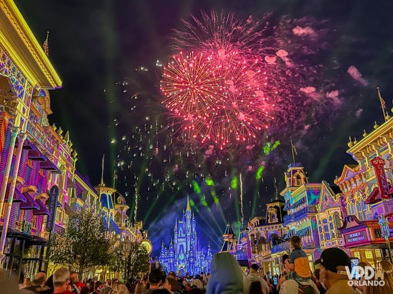 Foto do castelo da Cinderela no Magic Kingdom, iluminado em azul com os fogos de artifício no céu noturno. 