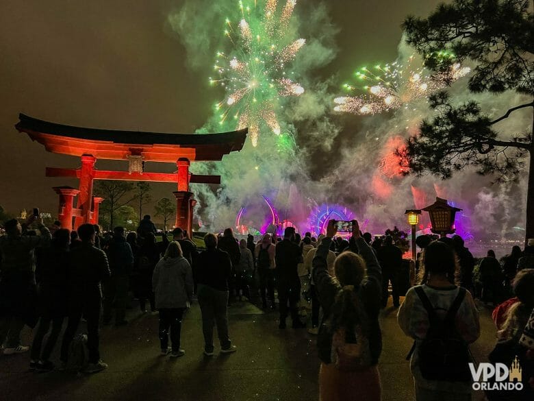 Imagem do lago do Epcot durante o show de fogos, com o ícone do pavilhão do Japão à esquerda e várias pessoas assistindo ao redor.