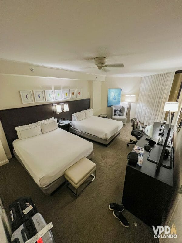 Foto de um quarto de um dos hotéis do Disney Springs, com duas camas queen, televisão e quadros na parede.