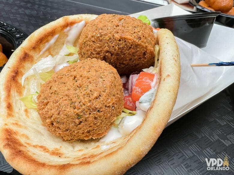 Foto de um sanduíche de falafel com dois falafels, alface, tomate e molho.