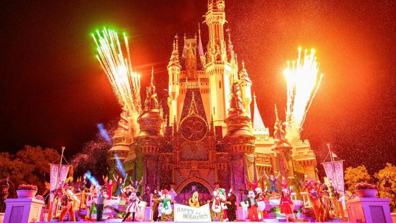 Foto de vários personagens em frente ao castelo, segurando uma plaquinha de Happy Holidays enquanto fogos disparam ao fundo. 