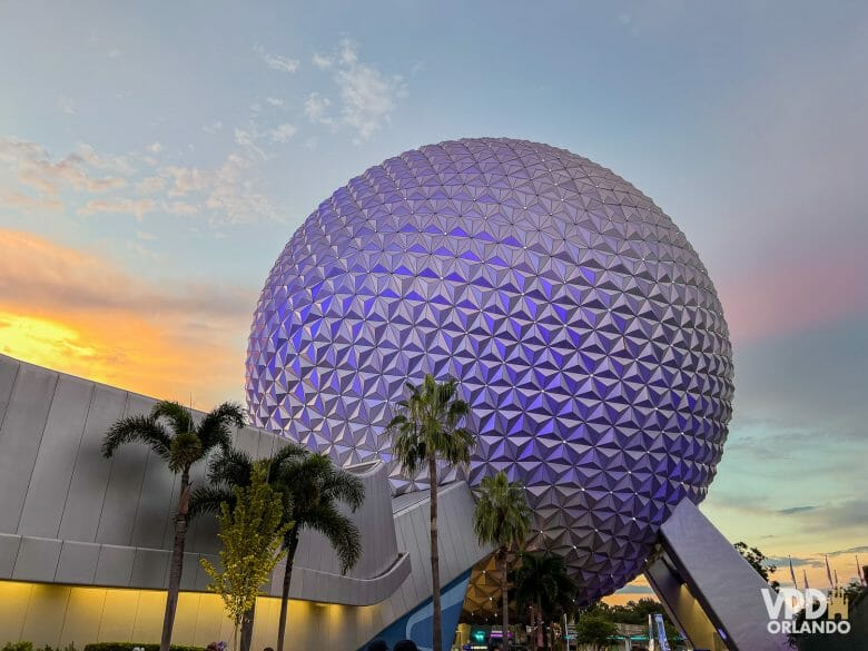 Foto da bola do Epcot no pôr do sol, iluminada com tons de roxo.