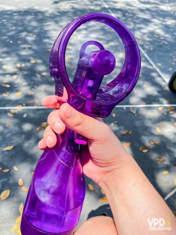 Foto de um ventilador de mão com spray de água roxo, um dos produtos que ajudam a combater o calor nos parques.