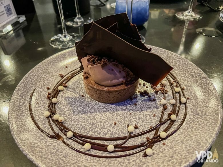Foto de uma sobremesa do Space 220, um cheesecake de chocolate que está coberto com lascas grandes de chocolate.