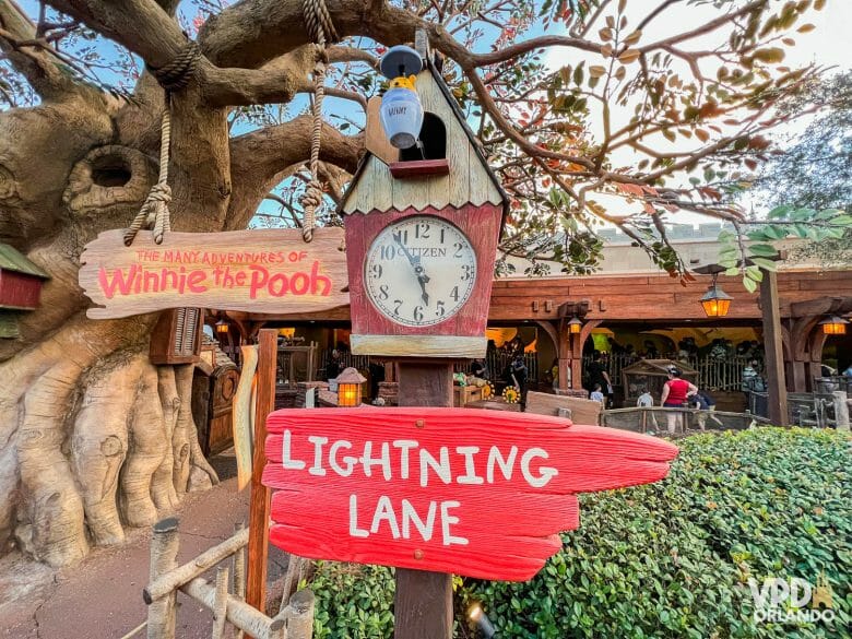 Foto da entrada da atração do Pooh, com um relógio e uma placa vermelha indicando a entrada de Lightning Lane