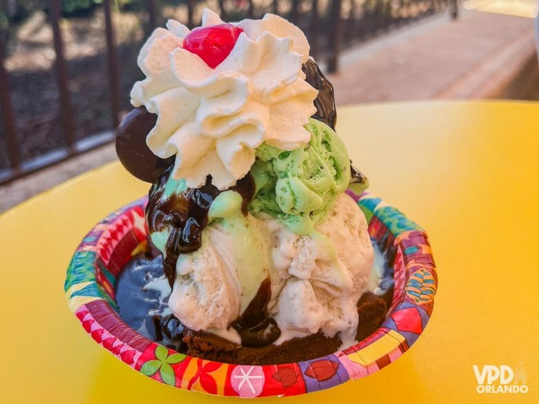 Foto de um sundae do Ice Cream Parlor, com sorvete de baunlha e de menta, chantilly, calda de chocolate e cereja.