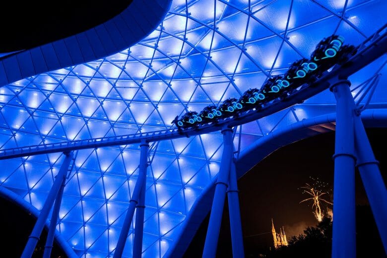 Foto de divulgação da Disney da montanha-russa de TRON. É noite e ela está iluminada em tons de azul, com o carrinho passando embaixo do "toldo".