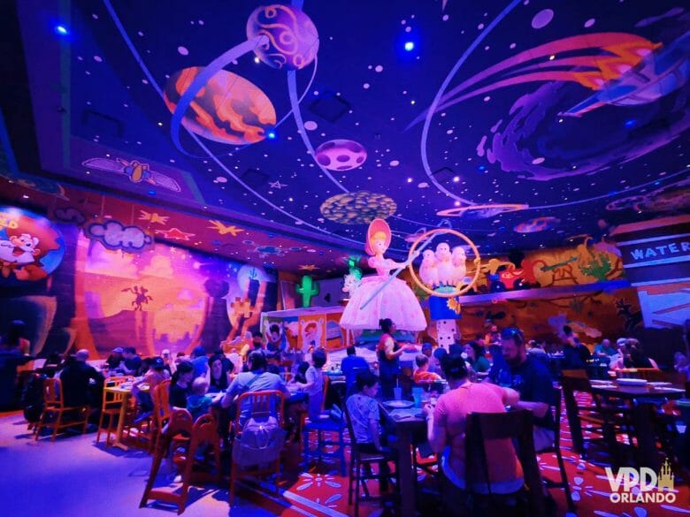 Área das mesas do novo restaurante de Toy Story, com a Bo Beep ao fundo e mesas espalhadas.