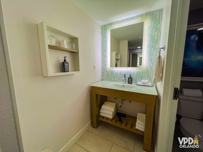 Foto da pia do banheiro do Dolphin, com espelhão e móvel de madeira.