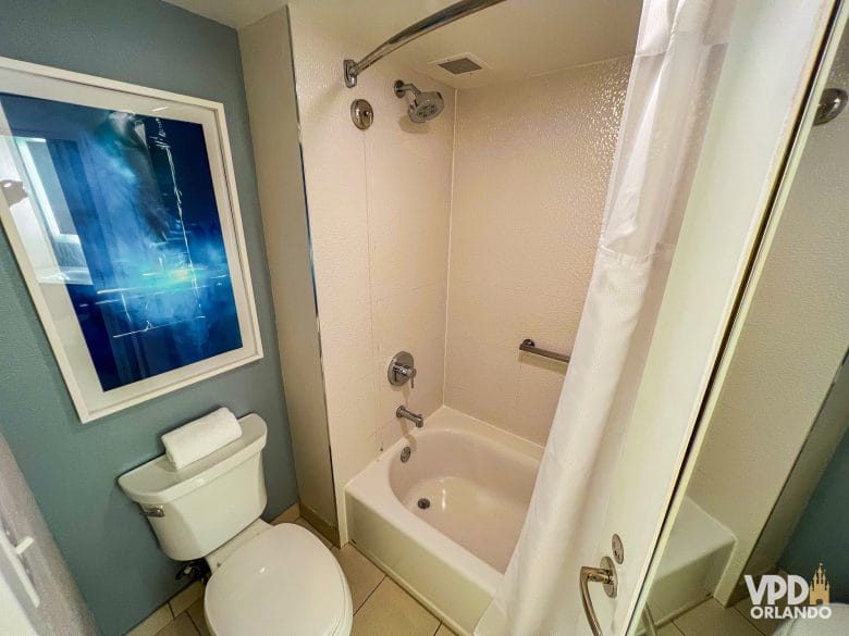 Banheiro do hotel, com banheira e chuveiro padrão e vaso sanitário.