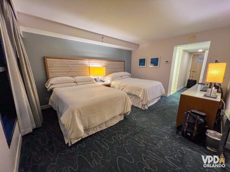 Foto do quarto do Dolphin, com duas camas, móvel pra tv e chão com carpete.