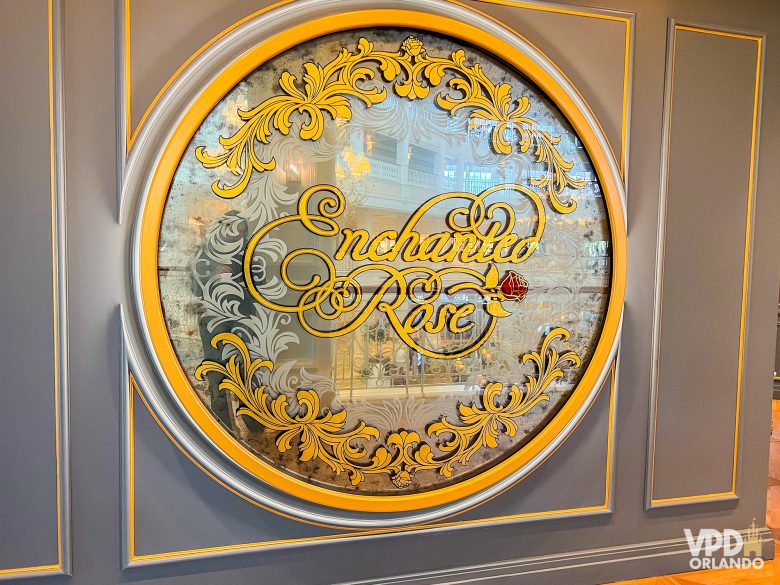 placa na entrada do enchanted rose, escrito em cursiva amarela com uma rosa ao lado.